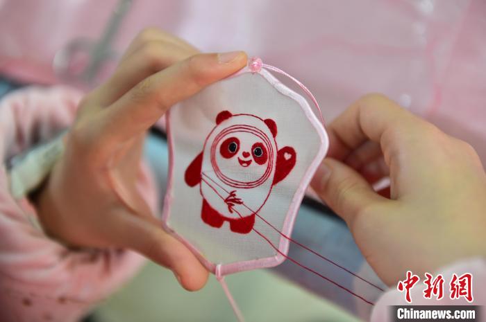 圖為一名小學(xué)生正在繡制2022年北京冬奧會(huì)吉祥物“冰墩墩”形象?！∮髟屏?攝