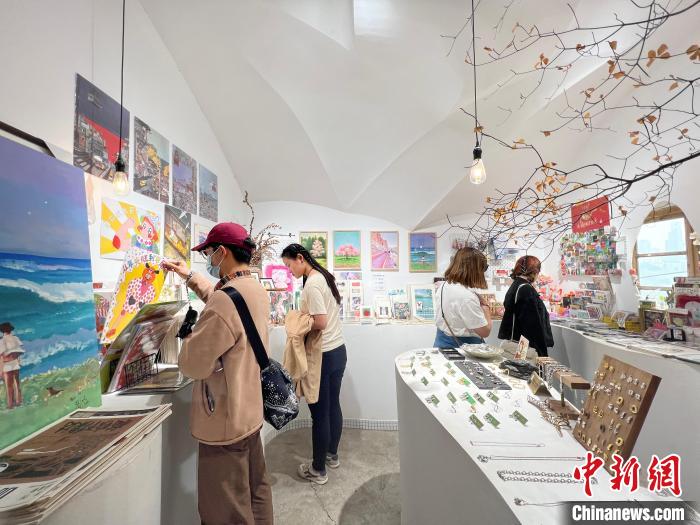 圖為藝術品商店內(nèi)，顧客挑選插畫作品?！＄婌?攝