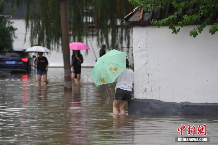 7月31日，市民行走在雨中的北京房山區(qū)瓦窯頭村。北京市氣象臺(tái)當(dāng)日10時(shí)發(fā)布分區(qū)域暴雨紅色預(yù)警信號(hào)。北京市水文總站發(fā)布洪水紅色預(yù)警，預(yù)計(jì)當(dāng)日12時(shí)至14時(shí)，房山區(qū)大石河流域?qū)⒊霈F(xiàn)紅色預(yù)警標(biāo)準(zhǔn)洪水。<a target='_blank' href='/'><p  align=