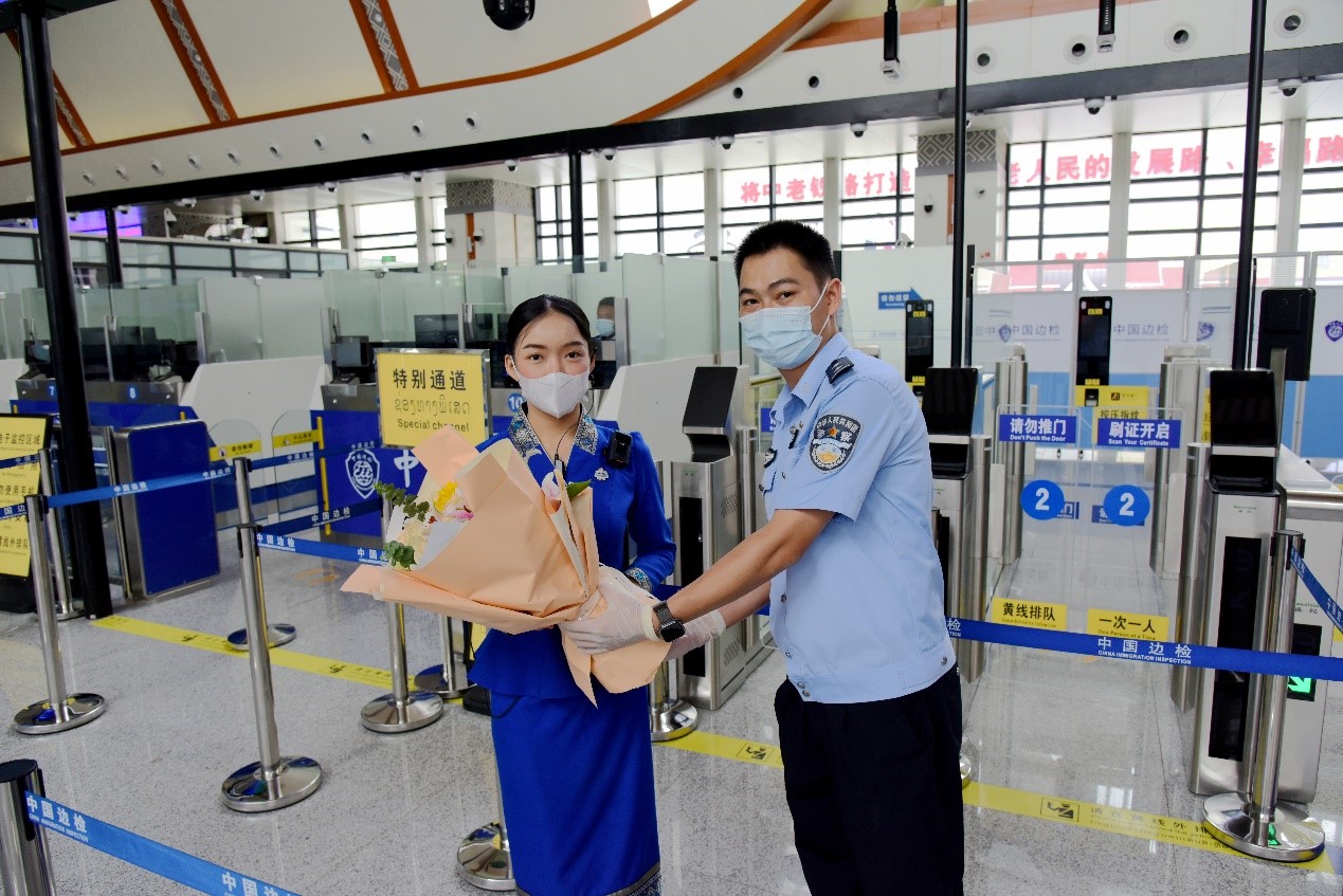 磨憨出入境邊防檢查站民警為中老鐵路第100萬名出入境旅客，D888次國際旅客列車老撾籍乘務(wù)員森達拉·妮緹婭（Sengdala Nitiya），送上鮮花。黃遠飛 攝