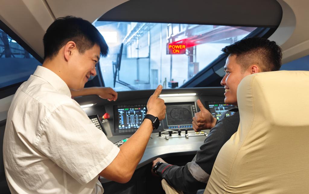 8月25日，在印度尼西亞萬隆的雅萬高鐵德卡魯爾動車所內(nèi)，中國師傅穆振（左）在向印尼火車司機塞蒂亞萬講解動車組出庫前的上電作業(yè)。