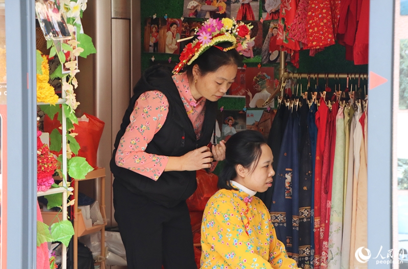 泉州府文廟附近，一名店主正為過(guò)路游客梳理頭發(fā)以佩戴“簪花圍”。人民網(wǎng) 黃東儀攝