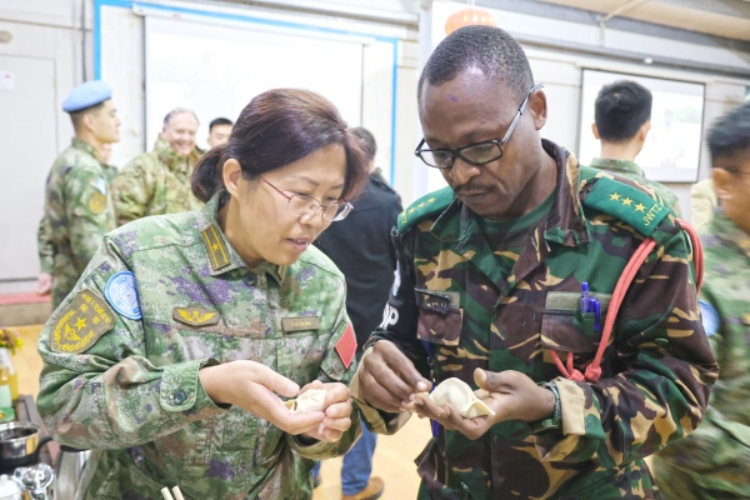 圖為維和官兵與外軍人員共同包餃子。胡光明攝