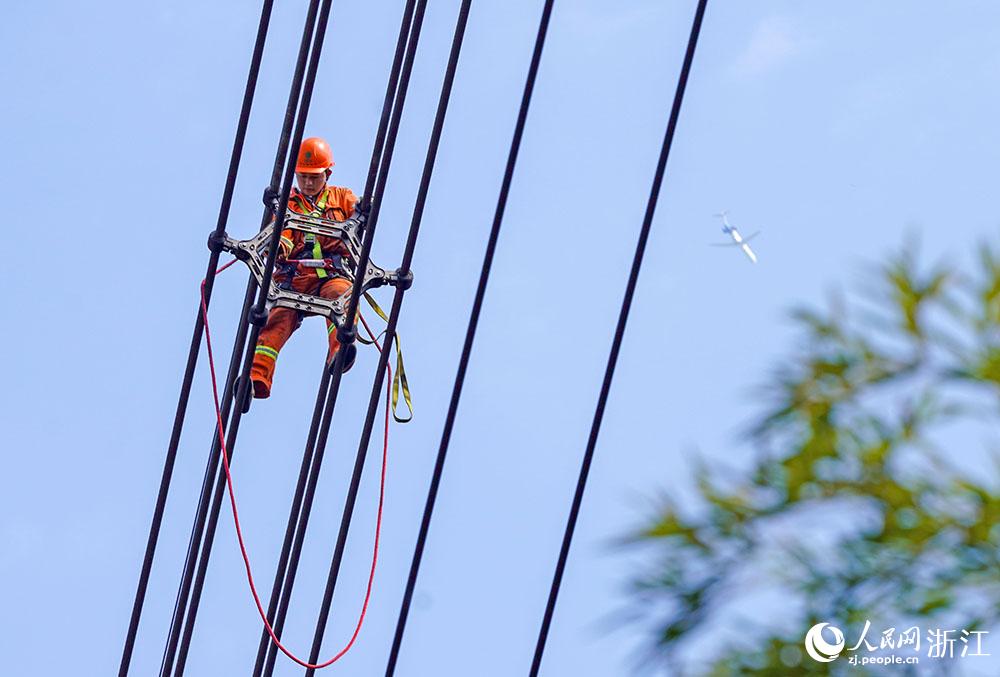 3月11日，在浙江省諸暨市河上鎮(zhèn)，浙江省送變電工程有限公司檢修人員在高空的導(dǎo)線上進(jìn)行線路檢修維護(hù)。人民網(wǎng) 章勇濤攝