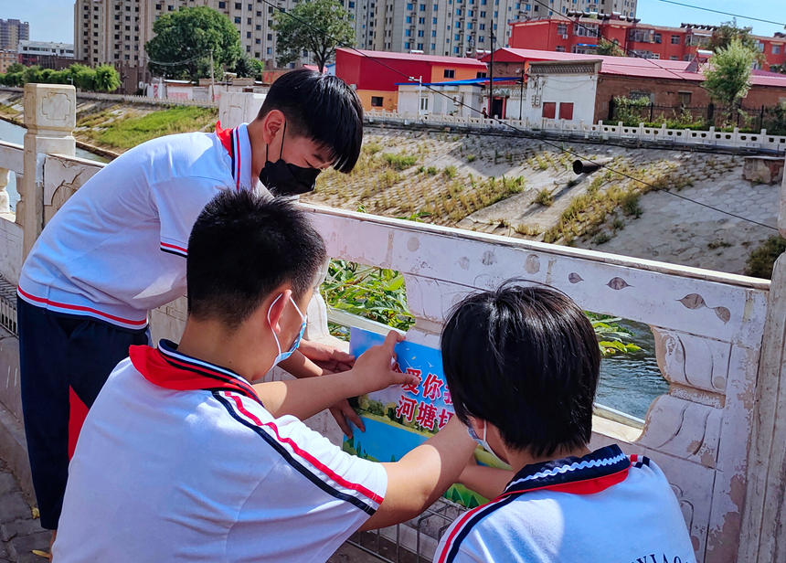 徐水小學(xué)學(xué)雷鋒志愿者在瀑河河邊張貼防溺水警示標(biāo)語(yǔ)。 徐水區(qū)委宣傳部供圖