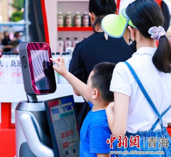圖為一名小朋友正在和機(jī)器人“志愿者”進(jìn)行互動(dòng)。 沐聞 攝