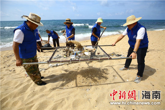 環(huán)保志愿者用篩網“淘”出海灘上的垃圾。