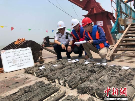 圖為勘察設(shè)計人員與海事局工作人員查看巖芯情況。　魏震 攝