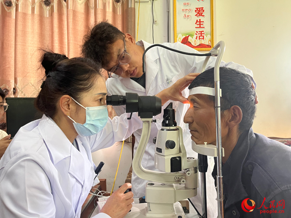 王紅英（左）和團隊成員為達(dá)熱村村民檢查眼睛。人民網(wǎng)記者 杜燕飛攝