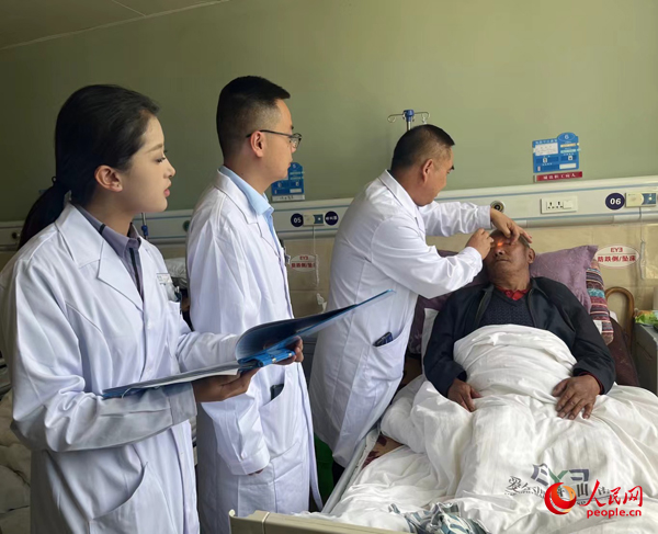 董光明（左三）帶領(lǐng)醫(yī)生對患者進行術(shù)前檢查。人民網(wǎng)記者 杜燕飛攝