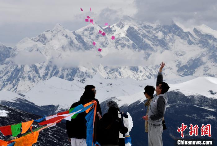 圖為5月14日，游客在西藏林芝色季拉山觀景臺(tái)拋灑“隆達(dá)”(風(fēng)馬旗，藏族民眾的一種祈福方式)?！±盍?攝