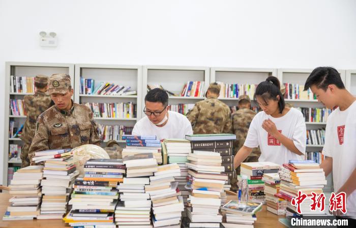 圖為志愿者們和邊防戰(zhàn)士整理圖書。　劉曉東 攝