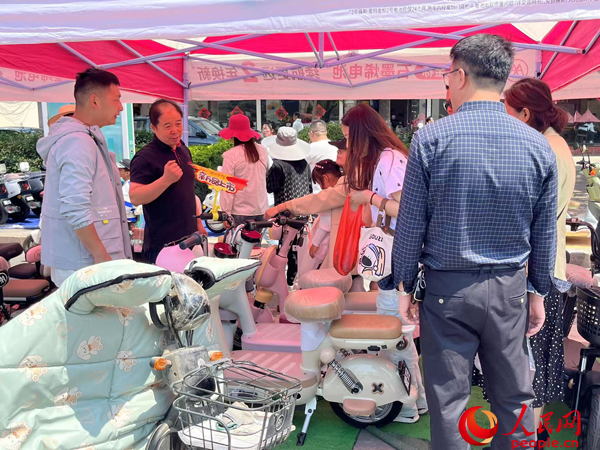 某電動自行車品牌工作人員向消費者介紹以舊換新相關(guān)情況。人民網(wǎng)記者 杜燕飛攝
