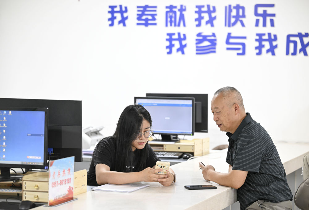 2024年6月20日，在寧夏銀川市金鳳區(qū)長城花園社區(qū)黨群服務(wù)中心，工作人員幫助居民辦理業(yè)務(wù)。圖片來源 新華社