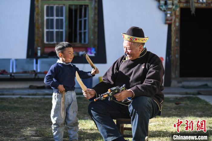 圖為米林縣扎西繞登鄉(xiāng)彩門村64歲的洛桑帶著孫子巴桑在院子的草地上玩耍?！『闻罾?攝