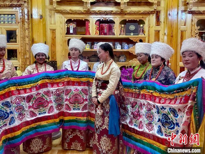 圖為女性展示村民自發(fā)繡制的“百米五彩哈達(dá)”?！±钣穹?攝