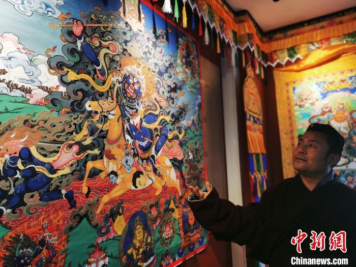 圖為久美尖措展示唐卡作品?！?zhí)砀?攝