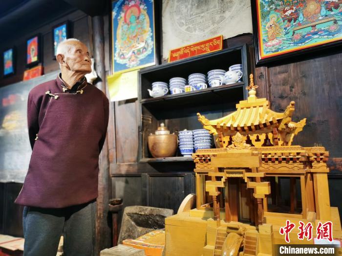 圖為古堡內(nèi)的藝人桑杰展示自己的雕刻作品?！?zhí)砀?攝