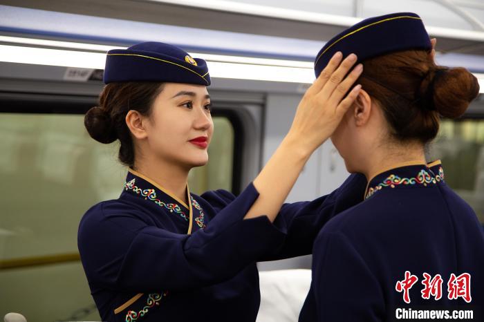 圖為青藏鐵路西格段“復(fù)興號(hào)”動(dòng)車組乘務(wù)員互相整理新制服?！±罾?攝