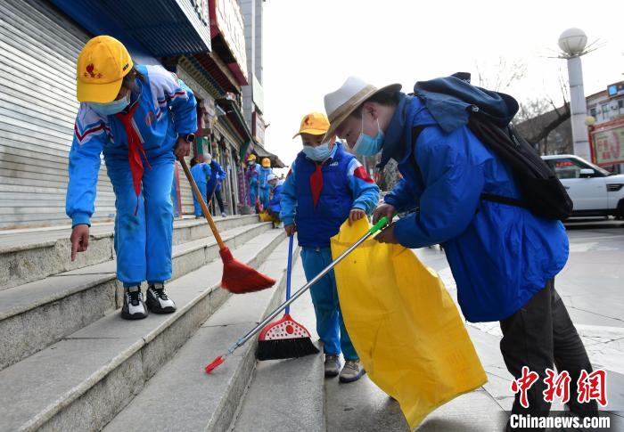 圖為拉薩市小學(xué)生打掃街道?！∝暩聛?lái)松 攝