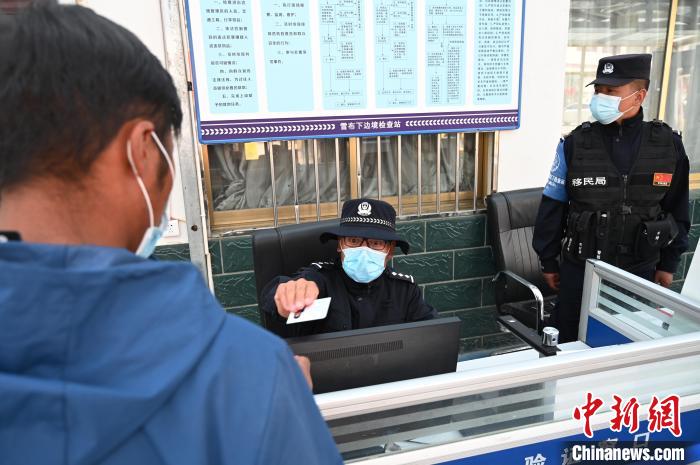 圖為移民管理警察登記完身份信息后將證件歸還給行人?！≮w朗 攝