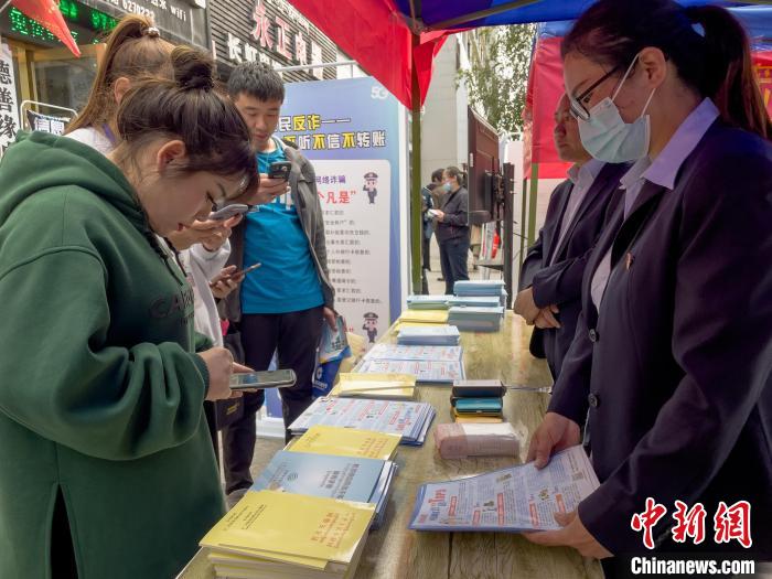 圖為工作人員正在向路過市民介紹國家反詐中心軟件的功能。　謝牧 攝