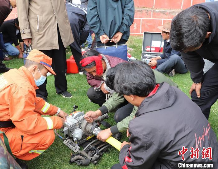 圖為森林消防員為護(hù)林員講解滅火裝備的使用方法?！〔际猩窒乐ш?duì) 供圖
