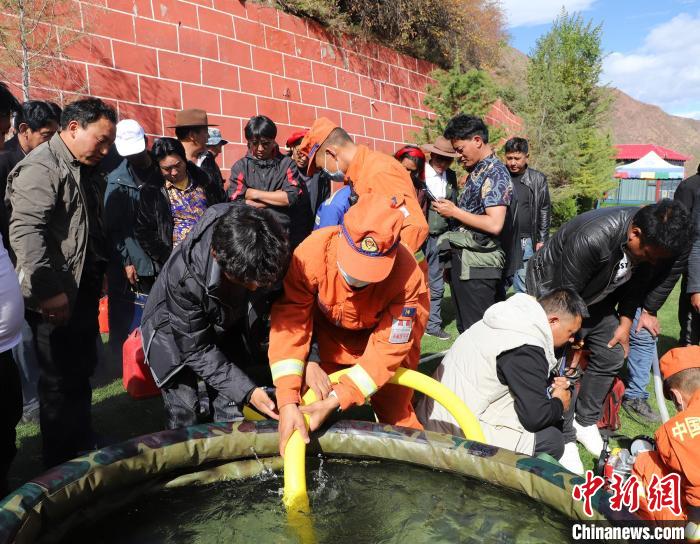 圖為森林消防員為護(hù)林員講解滅火裝備的使用方法?！〔际猩窒乐ш?duì) 供圖