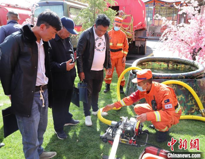 圖為森林消防員為護(hù)林員講解滅火裝備的使用方法?！〔际猩窒乐ш?duì) 供圖